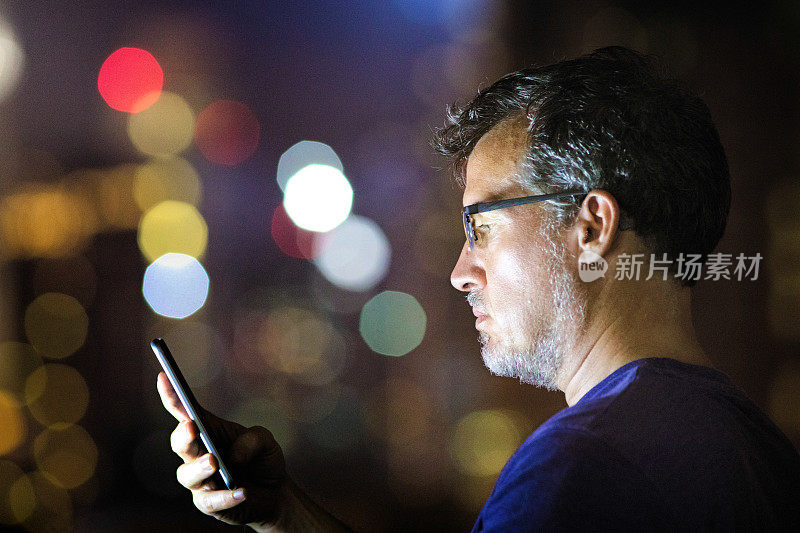中年男子在晚上工作时用手机