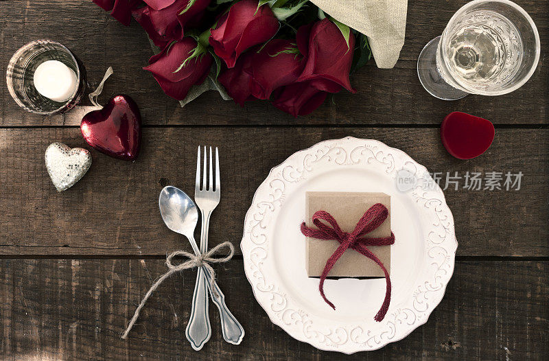 情人节晚餐，美酒和一份礼物放在一张旧木桌上