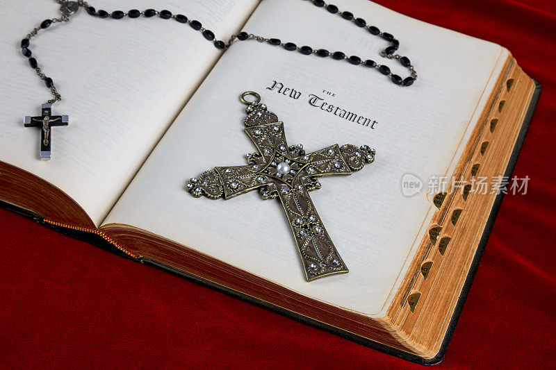 在新约页上有十字架和念珠的圣经