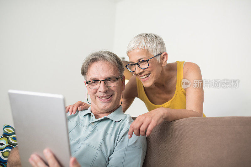 快乐成熟的女人抱着一个拿着平板电脑的男人