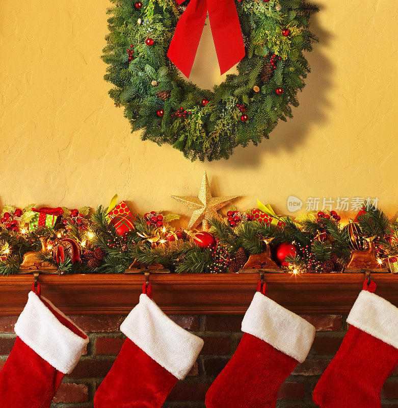 圣诞花环悬挂在圣诞装饰壁炉和四个长袜上