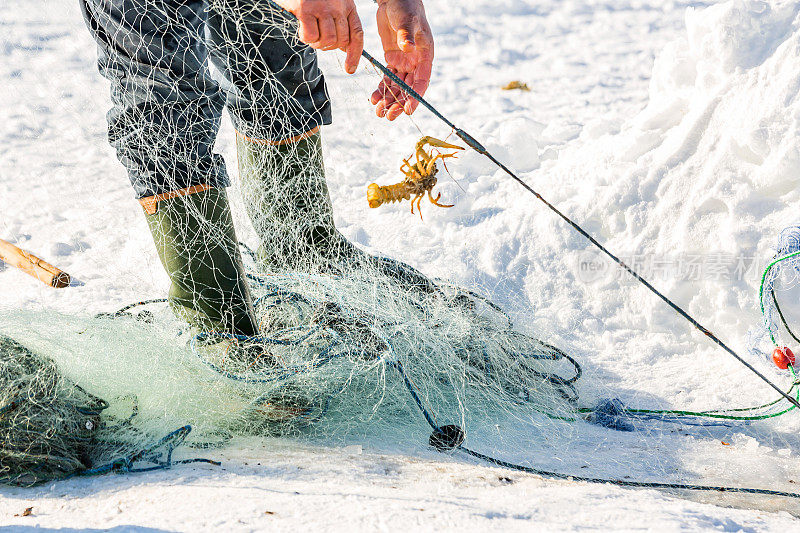 渔夫和小龙虾在冰冻的湖面上