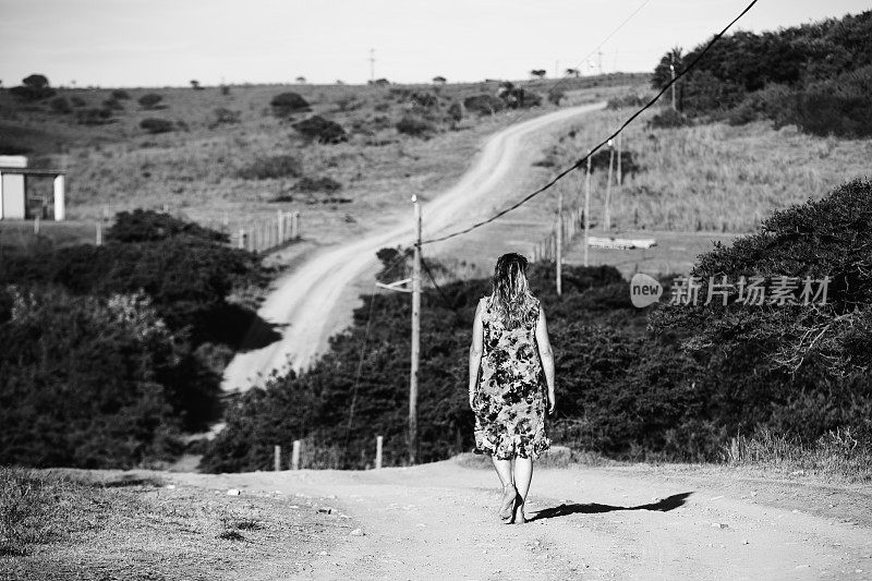 一个女人独自走在非洲的一条土路上