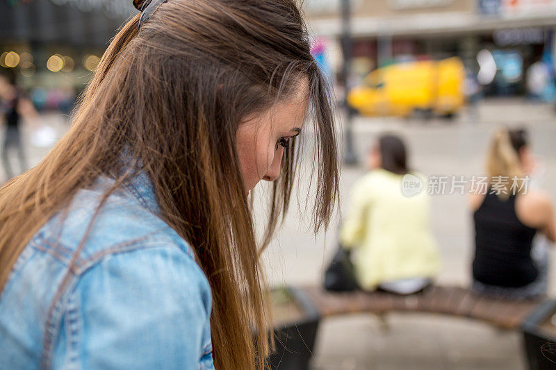 美丽的女孩走在繁忙的城市街道上，留着长发。穿着时髦的白色衬衫的女人。