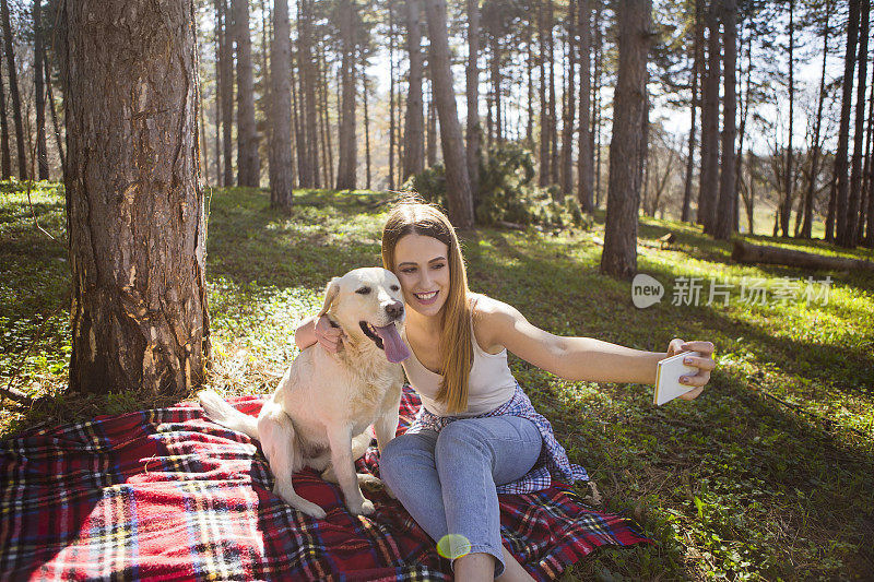 年轻女子和她的金毛猎犬在公园自拍