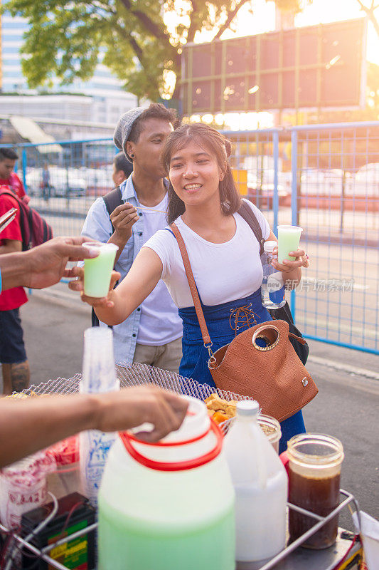 年轻的亚洲女人在街上买饮料