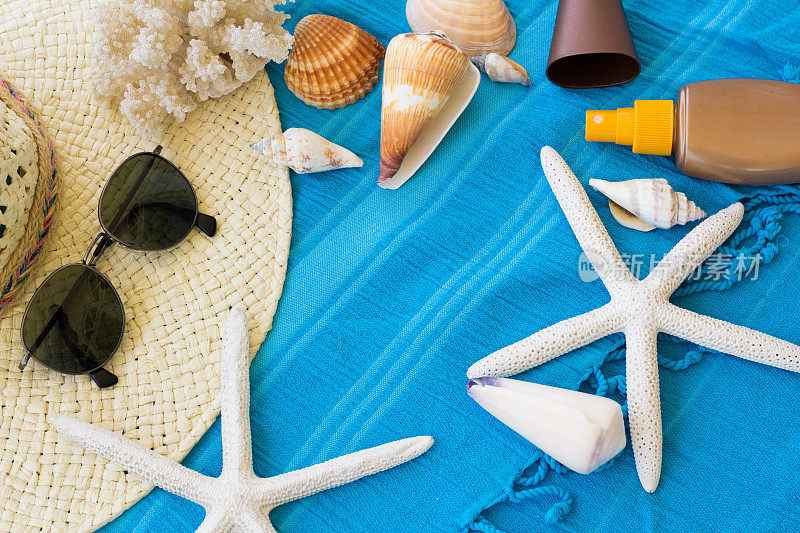 夏季配件背景。夏日海滩配件。海滩帽，海贝壳和海星鱼在一个绿松石蓝色海滩毛巾。热带夏季概念，航海生活概念。海滩背景，度假和旅游概念。
