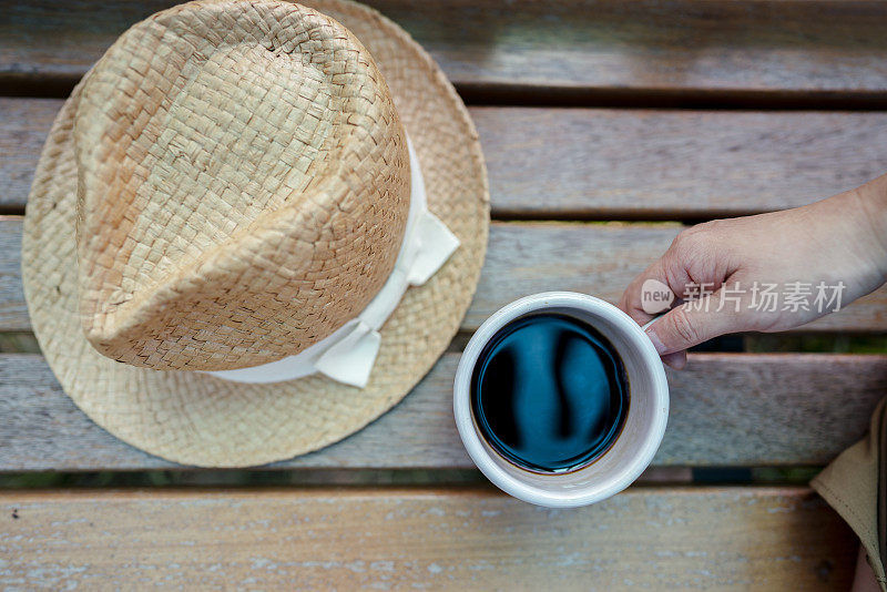 公园长椅上放着太阳帽和咖啡杯
