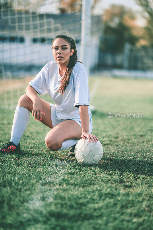 可爱的女足球运动员跪在球旁边