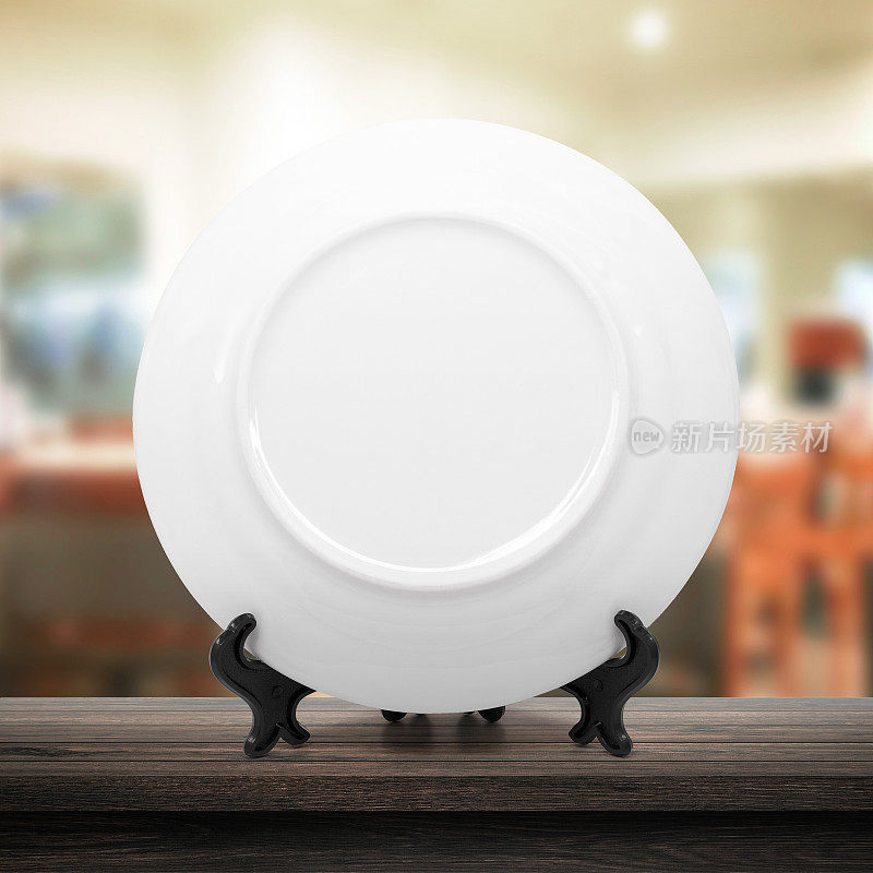 白色盘子或陶瓷盘子在现代厨房背景与空白餐具的概念。白色盘子模板放置在木桌上为您设计。