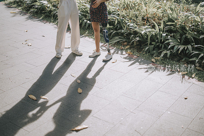 一个装了假肢的亚洲残疾妇女在公园里和她的朋友聊天