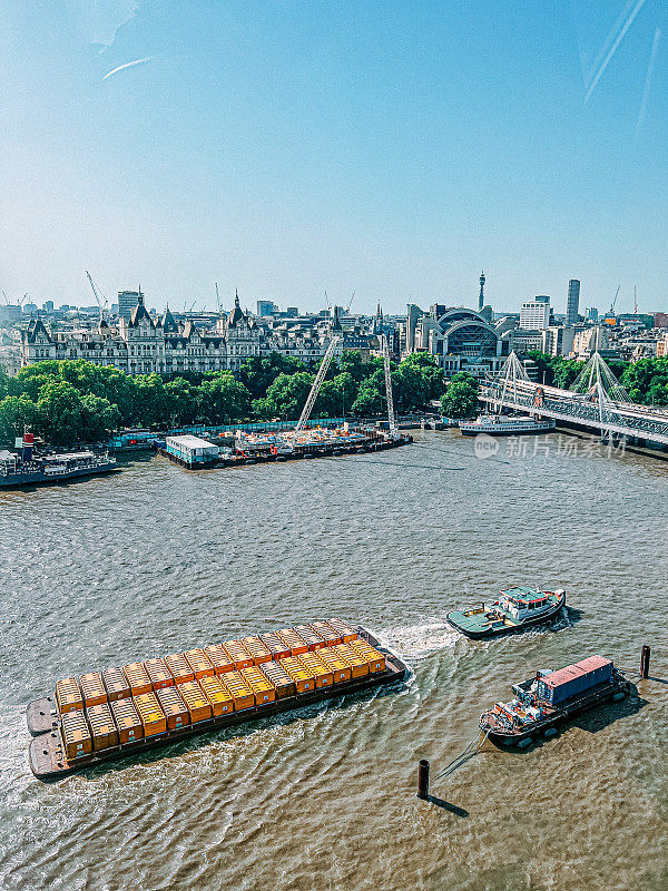 一艘工业货船沿着伦敦泰晤士河拉着集装箱的高角度视图
