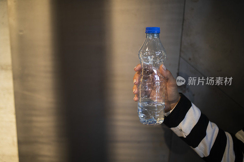 一个女人拿着一瓶水的手的特写