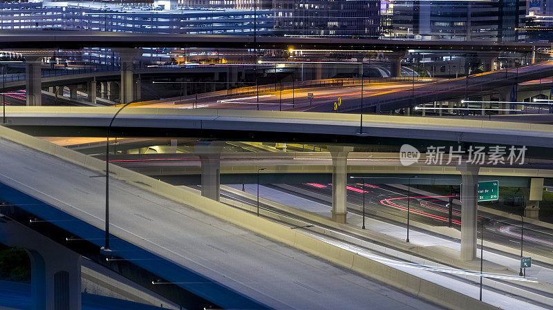 高速公路路口的夜间交通，车辆移动模糊，有灯光痕迹。