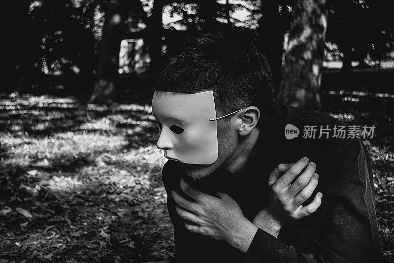 青年肖像戴着白色面具在树林里望向远方，黑白相间