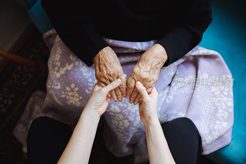 老女人的手牵着年轻女人的手，伸出援手，照顾老人的理念。