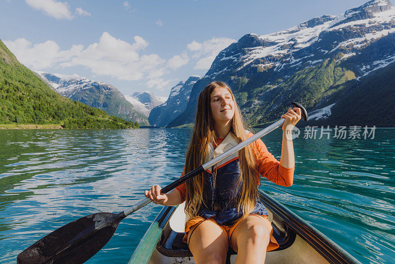 在挪威风景优美的Lovatnet湖上，微笑的女子在橙色独木舟的正面视图