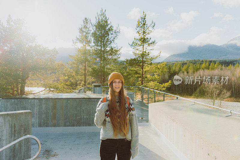 在挪威隆丹国家公园，背着双肩包的微笑女子凝视着山上的风景