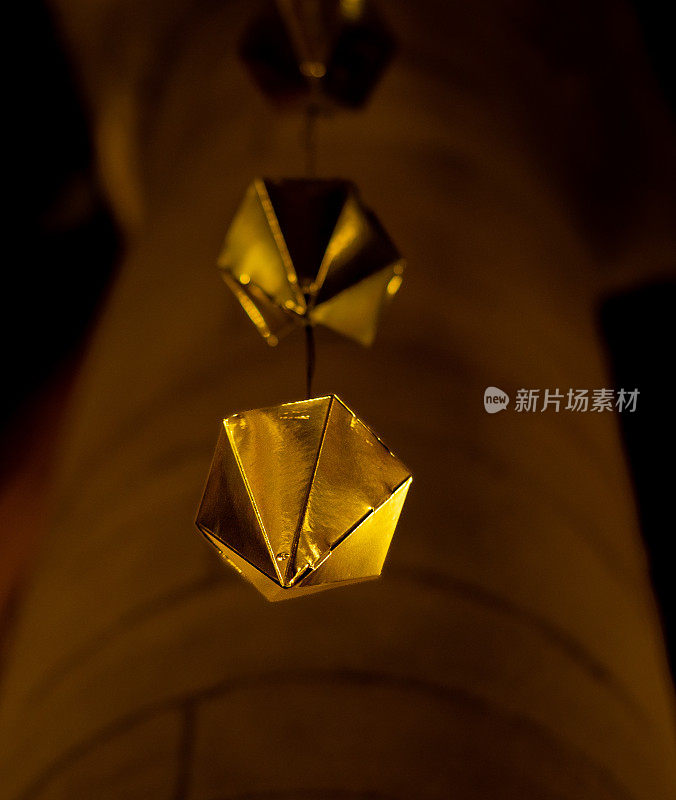 一颗金色钻石的低角度细节悬挂在granollers门廊的木质天花板上，随后是两颗以上的钻石。手机垂直比例视图。
