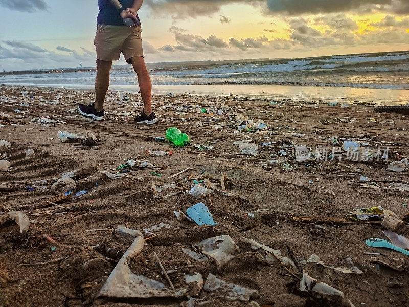 在海滩上走过一堆垃圾的面目全非的环保主义者