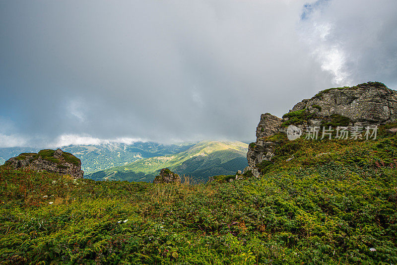 在一个阳光明媚的夏日里，有美丽的山峦和岩石景观。