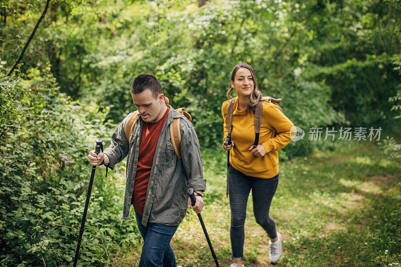 两个朋友，一个年轻的女人和一个患有唐氏综合症的男人，一起在森林里远足