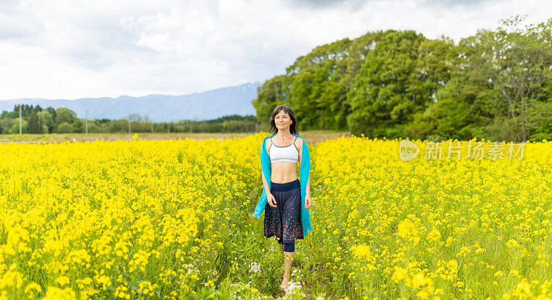 一位妇女在一片黄色的油菜花地里放松和享受户外活动