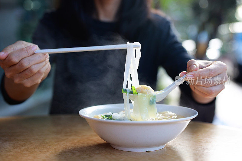 一名亚洲妇女在小贩摊上享受虾馄饨汤面的短镜头