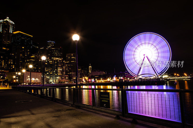 西雅图华盛顿天际线夜晚的城市灯光映照在太平洋上西雅图摩天轮点亮了69号码头的长时间曝光