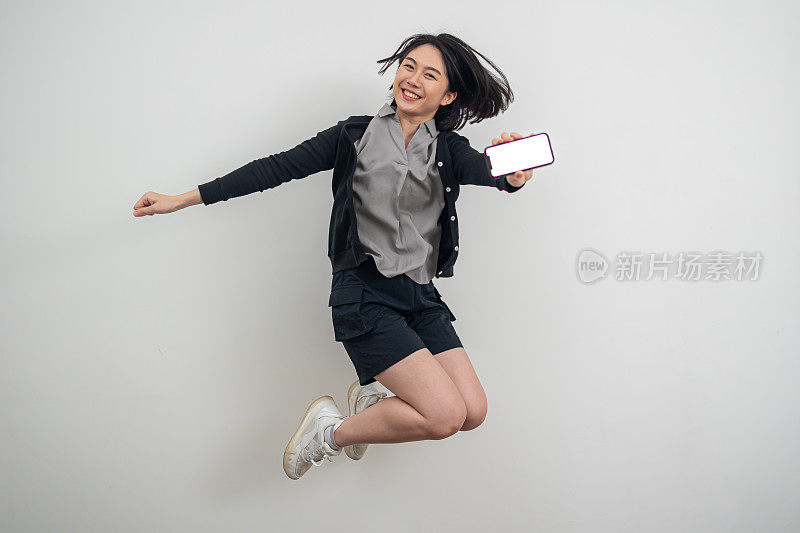 活跃的亚洲年轻女子拿着手机跳来跳去