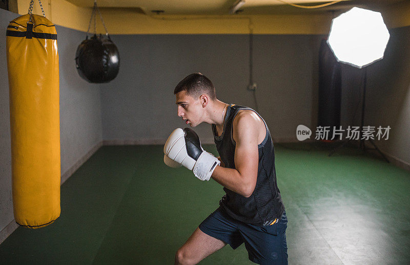 一名强壮的男性拳手在健身房训练，为拳击比赛做准备