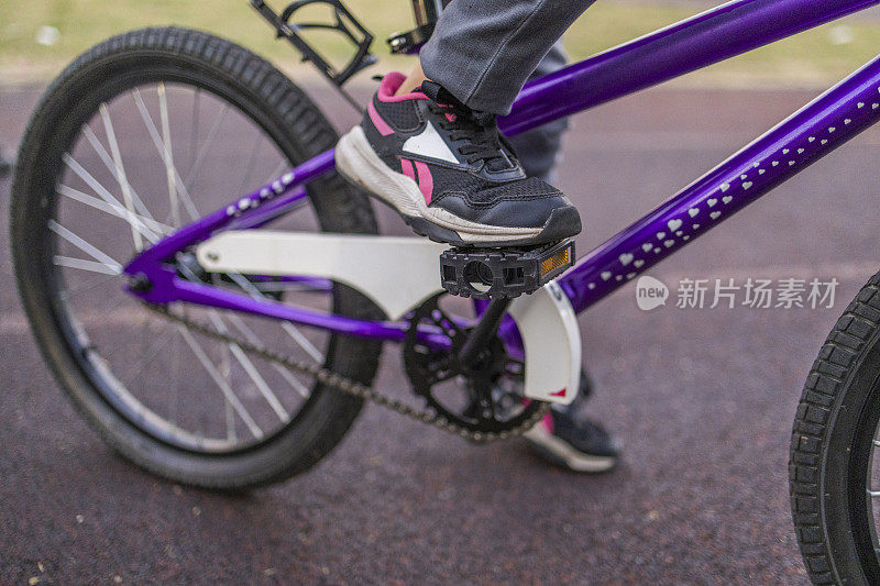 一个女孩的腿的特写照片，她踩着自行车踏板