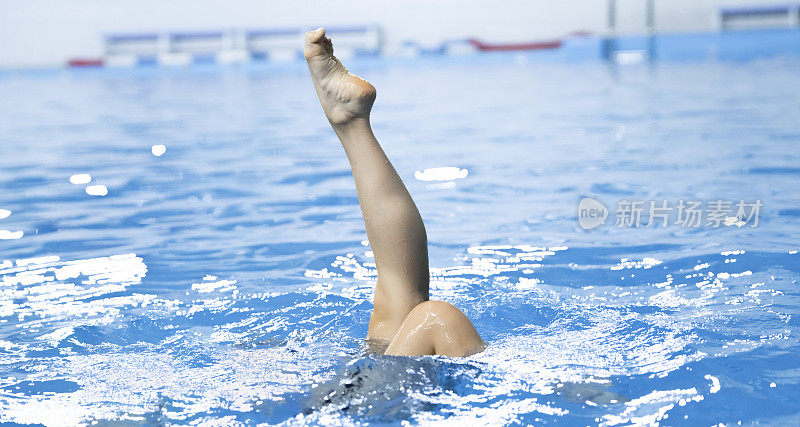 花样游泳女运动员独自在游泳池的水中练习新动作