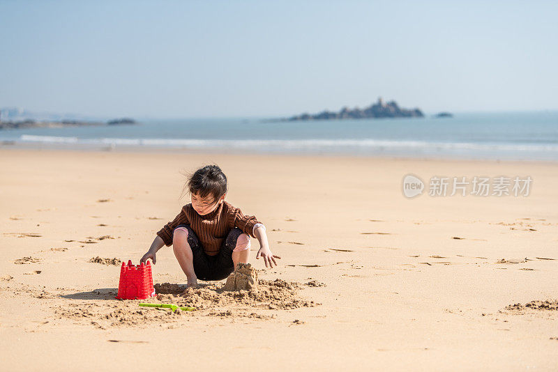 一个中国小女孩在沙滩上玩沙子