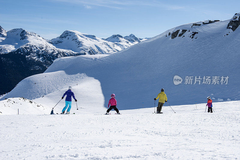 一家人在滑雪场滑下斜坡