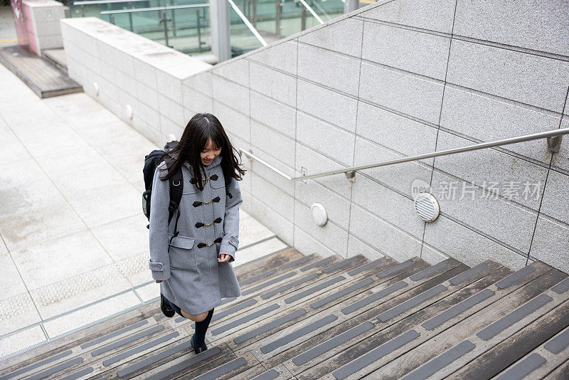 快乐的少女在城市里跑上台阶去上学