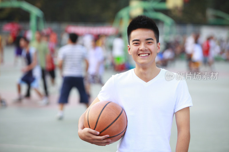 一个年轻的亚洲男孩拿着篮球