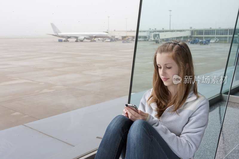 少女在机场候机时使用智能手机