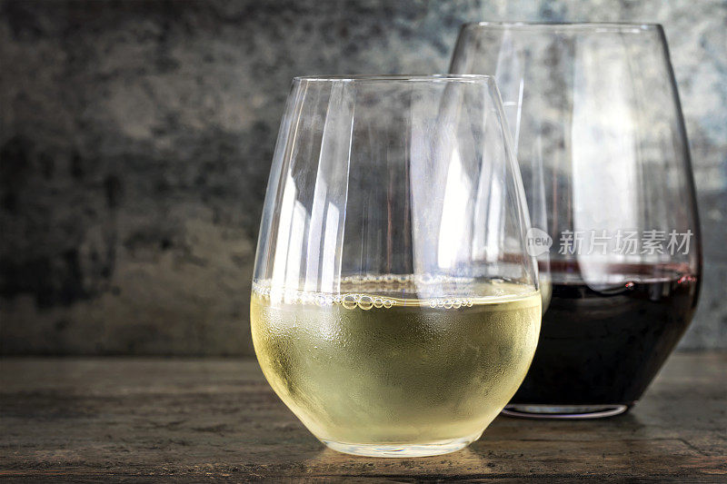 白葡萄酒和红酒在无茎杯与石板背景