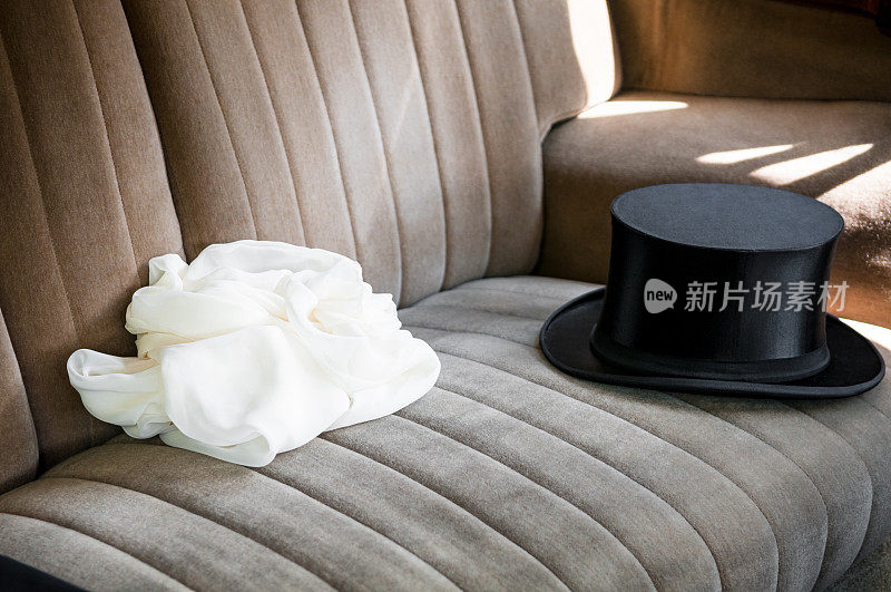 高顶礼帽和白色的婚纱在一个lomousine后座上