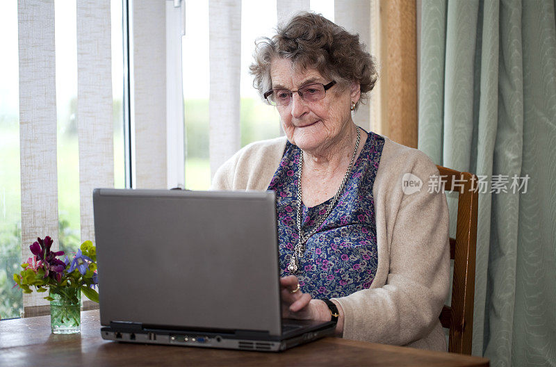 用笔记本电脑工作的老年妇女