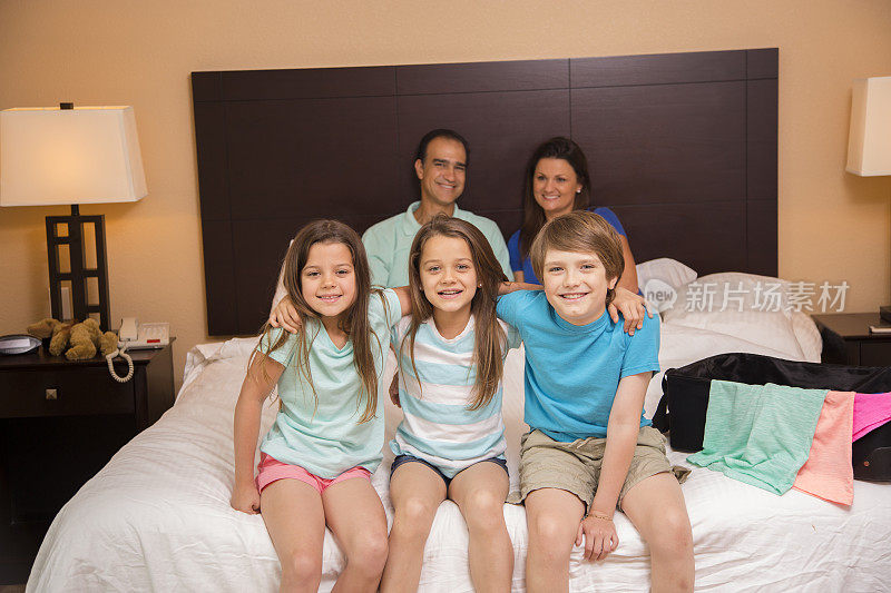 家人在酒店房间里。孩子们在床上的前景。假期。快乐。