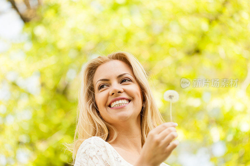 微笑的女人拿着蒲公英