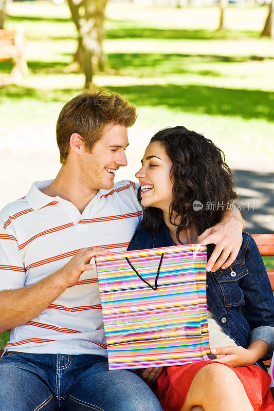 一对夫妇在公园里拿着购物袋