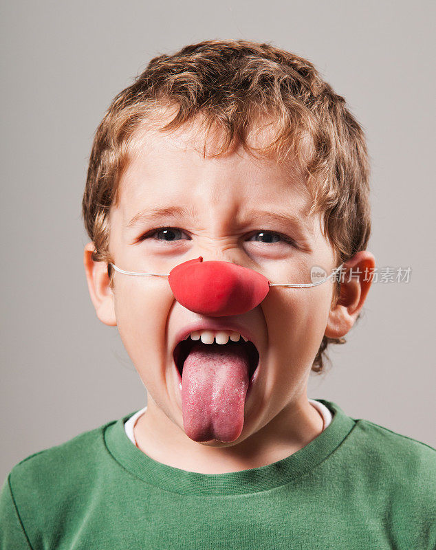 长着小丑鼻子露出舌头的金发小孩