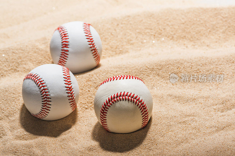 三个棒球放在沙滩上
