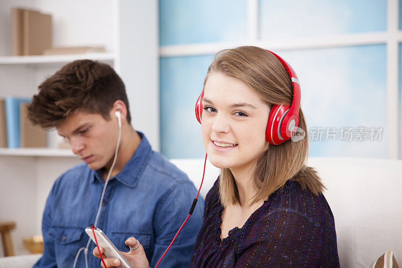 青少年朋友通过耳机和手机分享音乐。首页