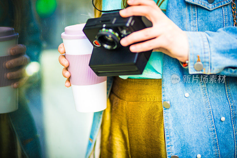 女孩手拿咖啡杯和复古相机的细节