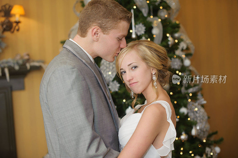 婚礼当天，新郎在圣诞树旁亲吻新娘