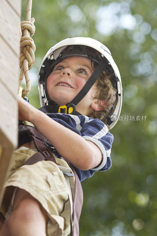 快乐的小男孩爬在木石墙上